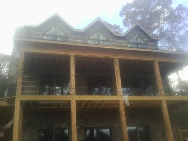 Dormers and porch framing on a large log home under construction — Roof Coating work by our crew in Hamlet