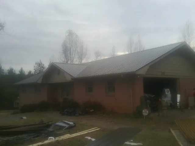 Gray metal roof on a stucco house with an attached garage in Hamlet