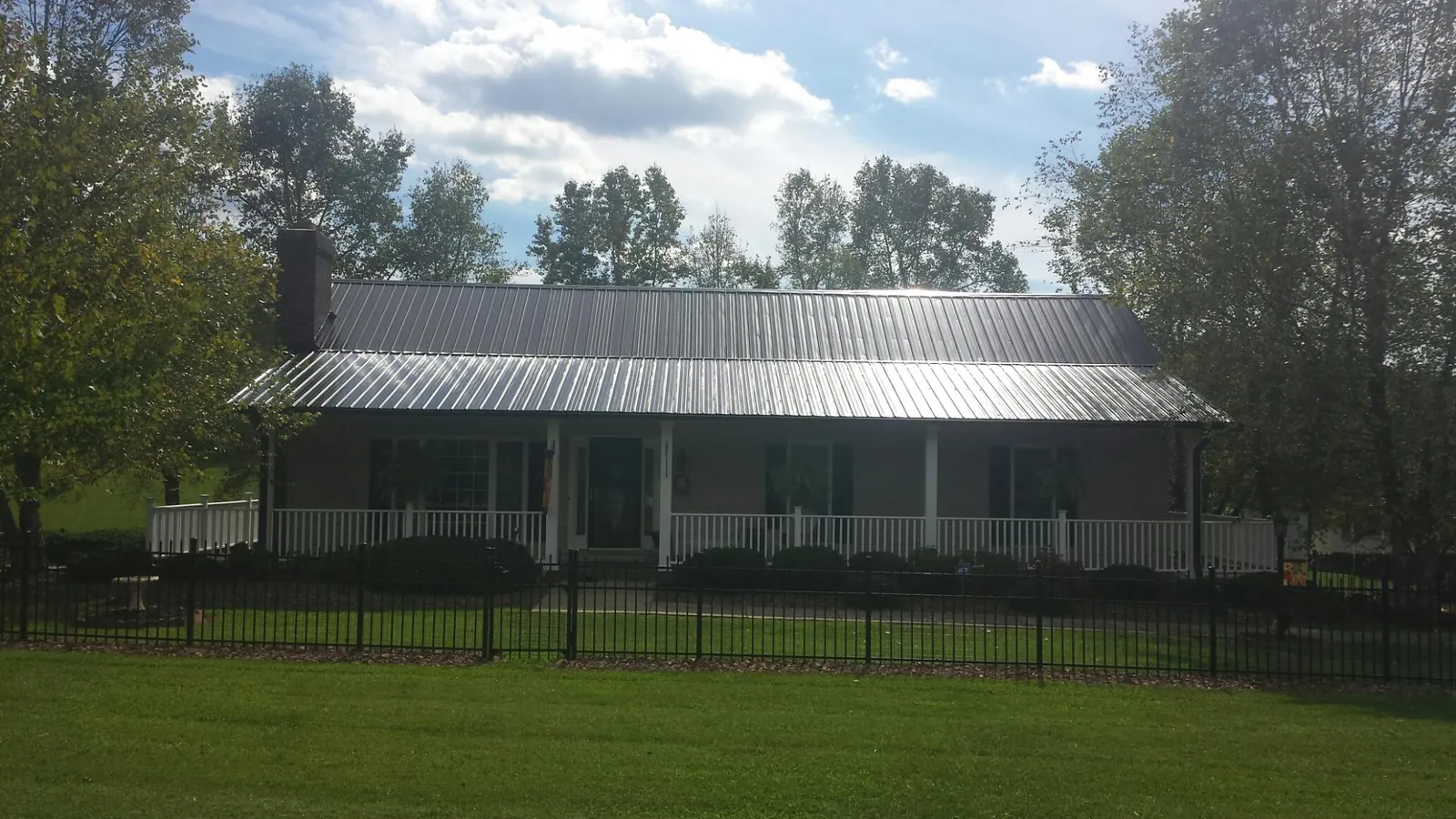 Gray metal roof on a brick ranch with a full width front porch — Gutter Guard Installation work by our crew in Hamlet